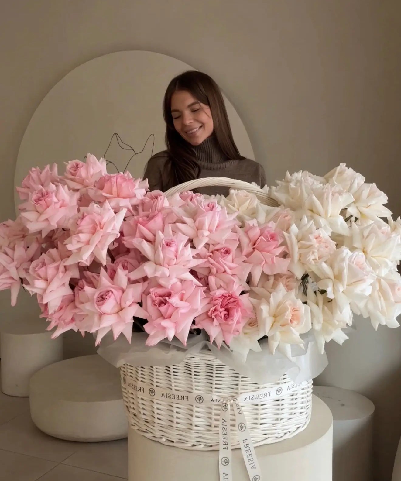 Woman with large basket of fresh pink and white roses in modern floral studio
