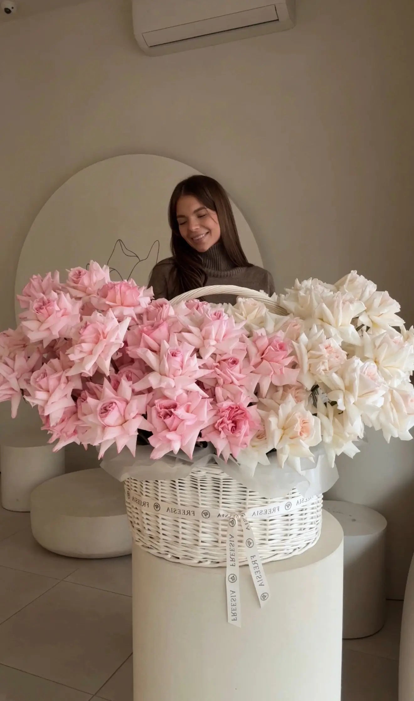 Woman with large basket of fresh pink and white roses in modern floral studio