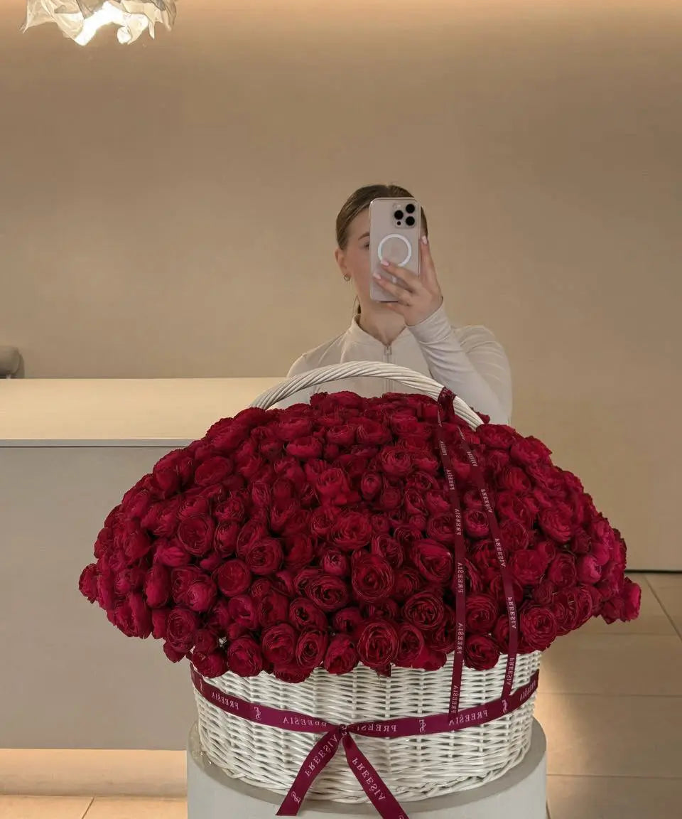Large basket of fresh red roses with ribbon, floral arrangement in modern interior