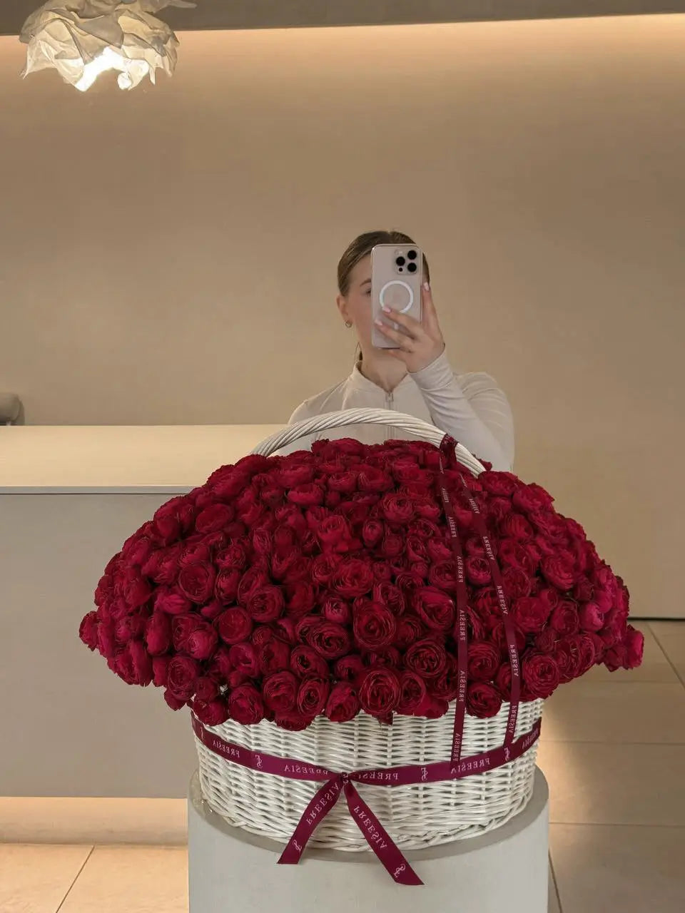 Large basket of fresh red roses with ribbon, floral arrangement in modern interior