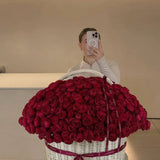 Large basket of fresh red roses with ribbon, floral arrangement in modern interior